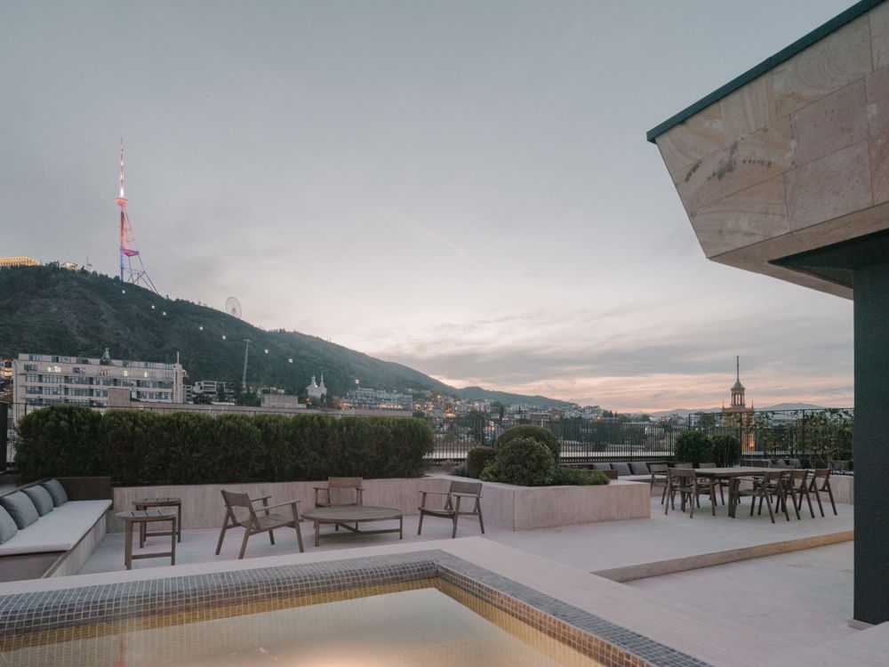 The Grand Terrace Club Suite featuring a private balcony, separate living area, and access to the Club Lounge, styled with contemporary Georgian décor and a 75-inch smart TV